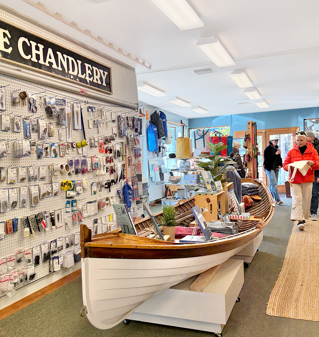 Nautical supply store interior with a wooden boat display and wall of marine gear behind it.